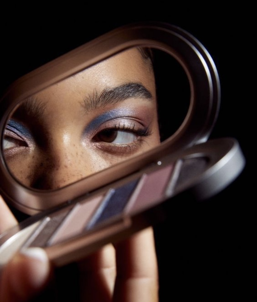 Chica sosteniendo una paleta de maquillaje mientras mira a sus alrededores.