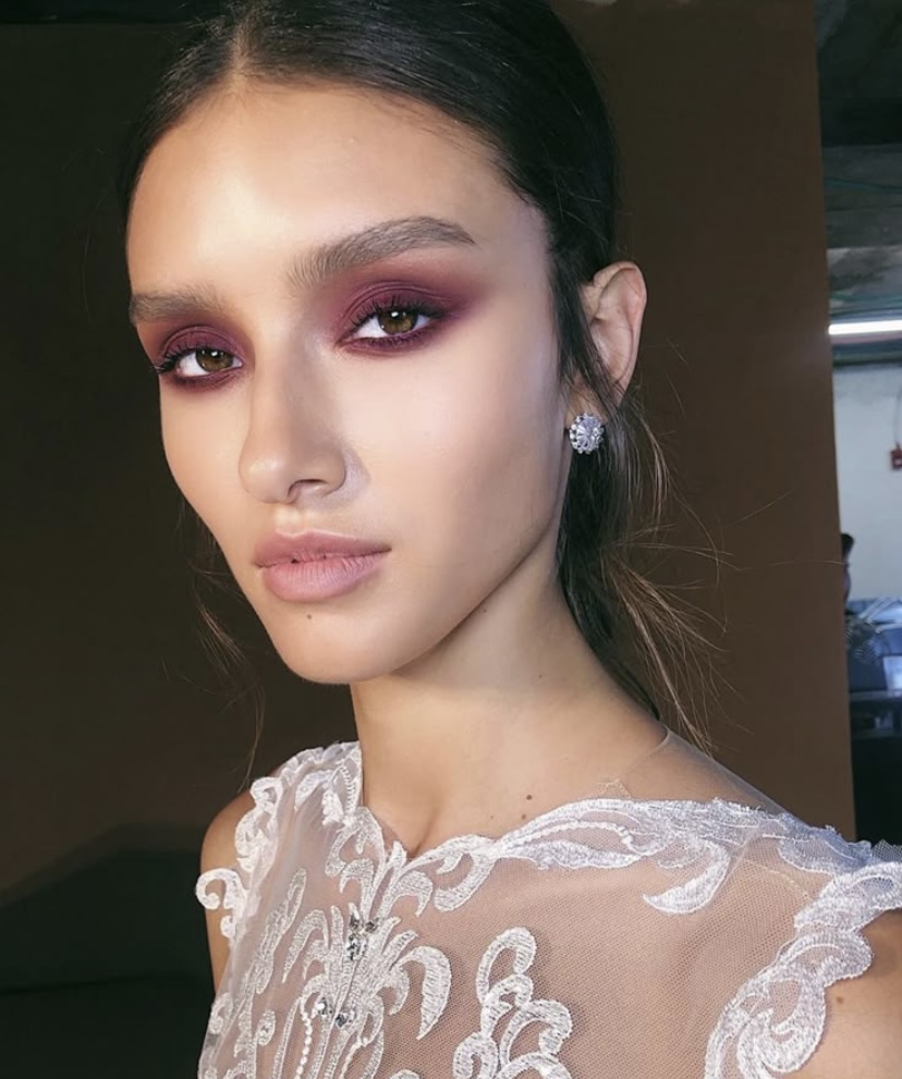 Mujer con maquillaje de ojos en tonos rosados y piel luminosa