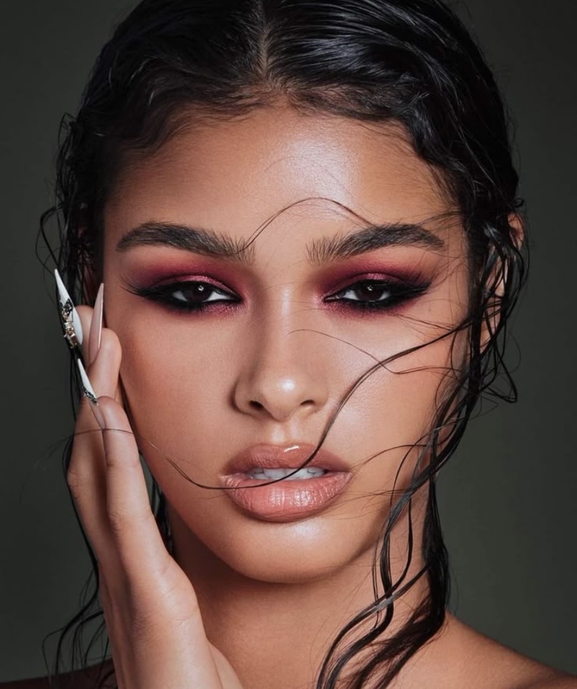 Mujer con maquillaje de ojos en tonos rosados y delineado fuerte en color negro.